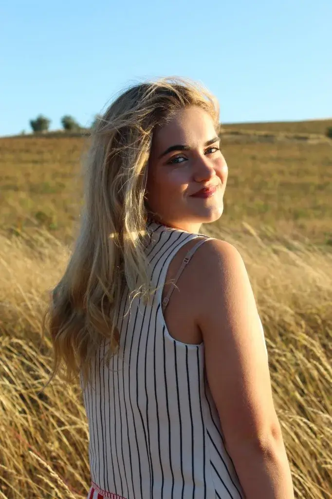 Indiana smiling softly over her shoulder in a golden field.